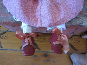Miss "A"'s hand made red leather shoes are trimmed in hand dyed silk ribbons that have been carefully matched to faded antique originals.