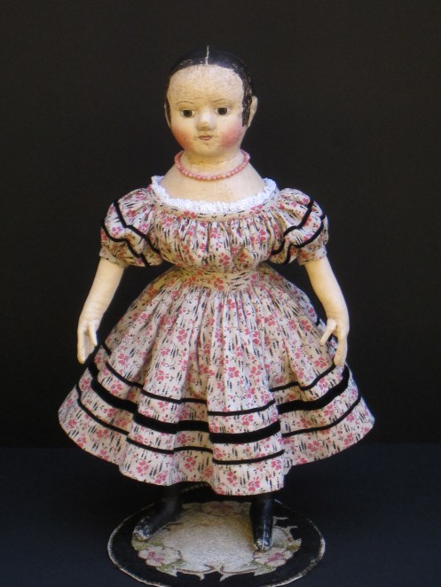 Her dress made from antique pink and black print fabric is adorned with rows ans rows of black velvet ribbon.