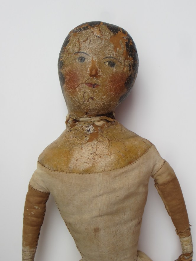 The neck of the doll suffered a lot of wear and tear over the years.  Portions of the painted cloth are missing.
