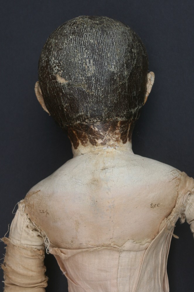 I was asked to bring back some of the original color to the face and shoulders of this early doll. Years of sun fading and a prior overly vigorous cleaning had turned the doll's once skin toned paint almost white.