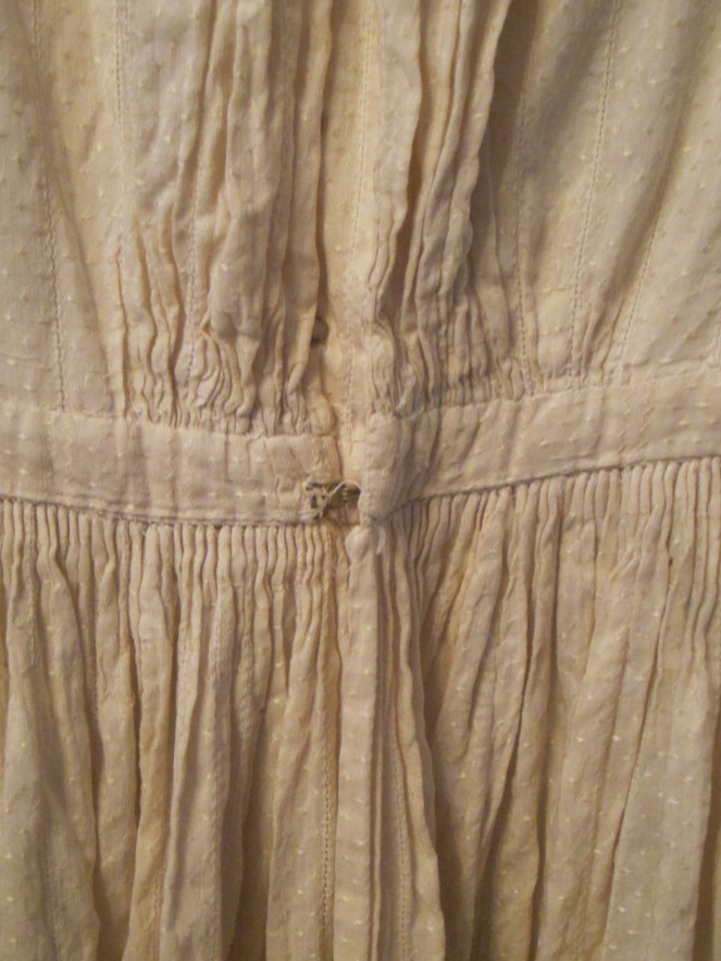The back of the dress is fastened with large brass hooks and eyes.
